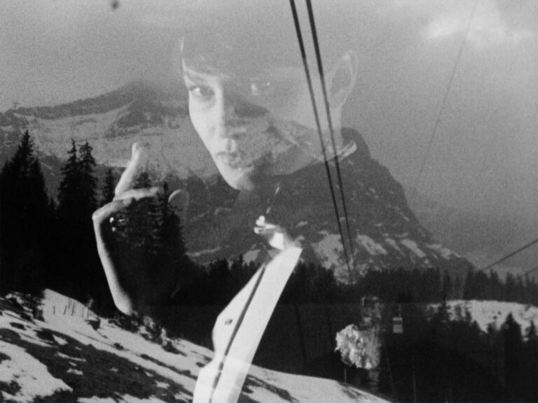 A still image from Sandra Lahire's film called Eerie. A black and white image of a young woman's face superimposed over a scene of the snowy mountains and a cable car