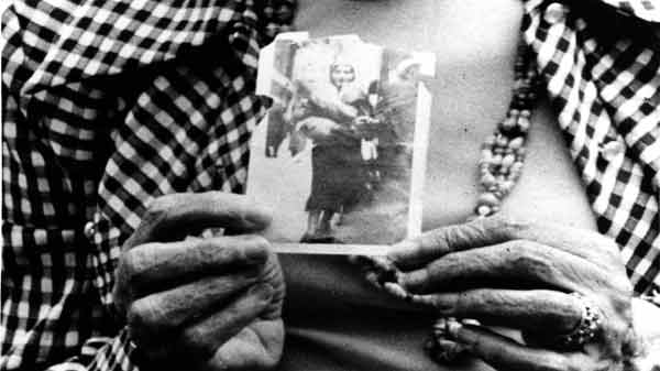 A still image from Betzy Bromberg's film Ciao Bella or Fuck Me Dead. A black-and-white close-up of a person holding a photograph close to their chest