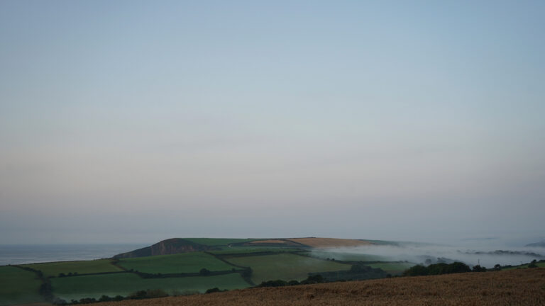 Landscape image of a clear sky and and low hanging cloud over a cliff