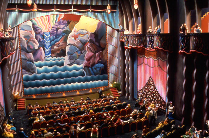 Colourful animation of a packed theatre with a waterfall and sky bursting with colour on-stagen