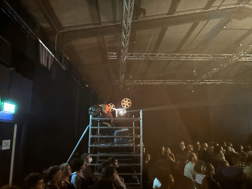 Michael Higgins projecting 16mm above the audience at DISSOLUTIONS Festival 2024